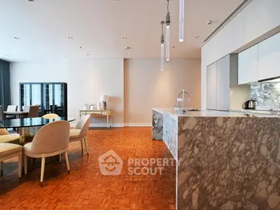 Luxurious open-plan kitchen and dining area with marble island and parquet flooring.