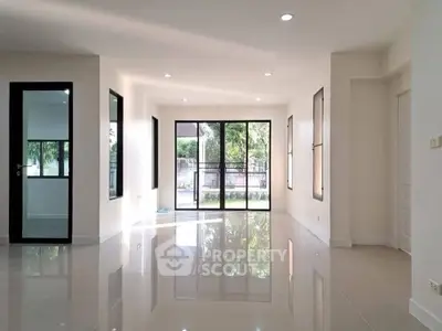 Spacious modern living room with large windows and glossy tiled floors