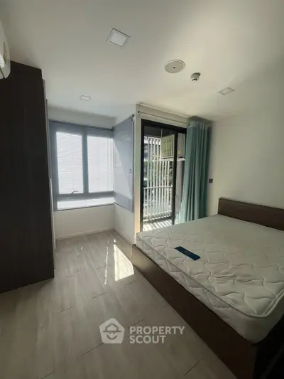 Bright bedroom with large window and modern furnishings in a stylish apartment.