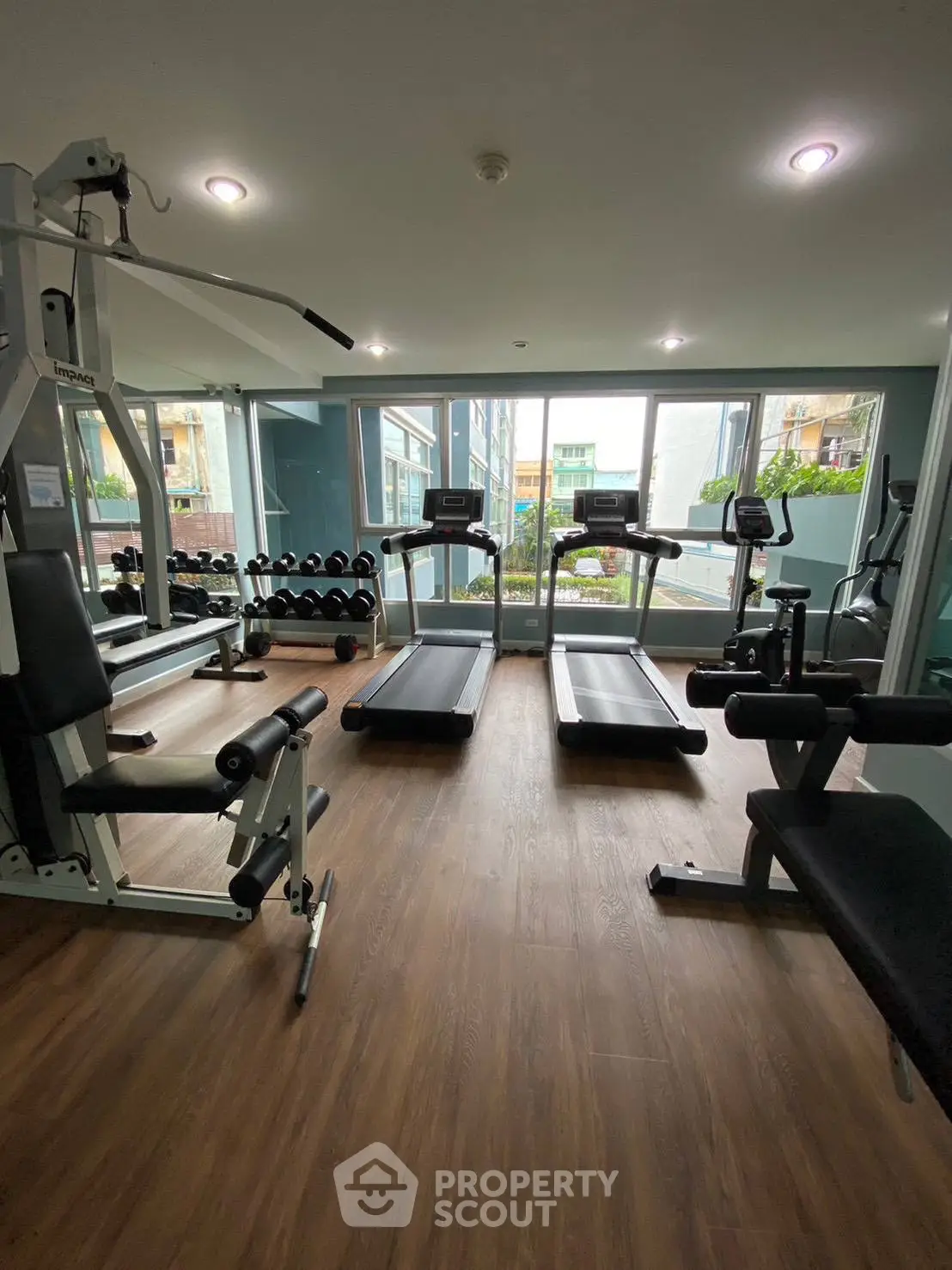 Modern gym with state-of-the-art equipment and large windows in a residential building.