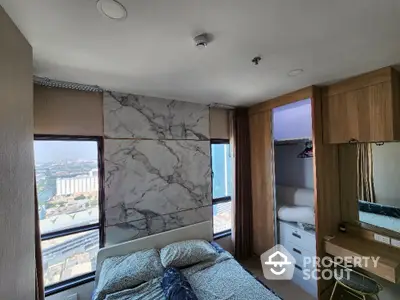 Cozy bedroom with a stunning city view, featuring a large window, modern furnishings, and a comfortable bed, perfect for urban living.