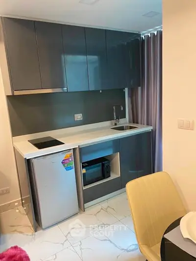 Modern compact kitchen with sleek cabinetry and integrated appliances in a stylish apartment.