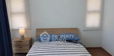 Cozy bedroom with striped bedding and wooden furniture, perfect for relaxation.