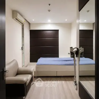 Modern bedroom with sleek design, featuring a comfortable bed, stylish sofa, and large mirror for a spacious feel.