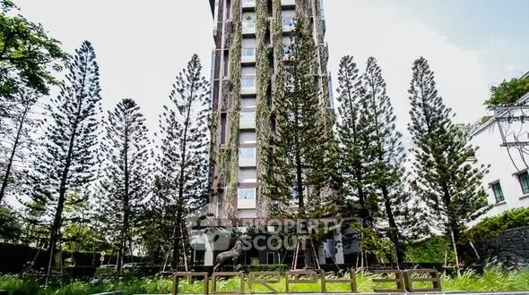 Stunning modern building with lush greenery and tall trees in urban setting.