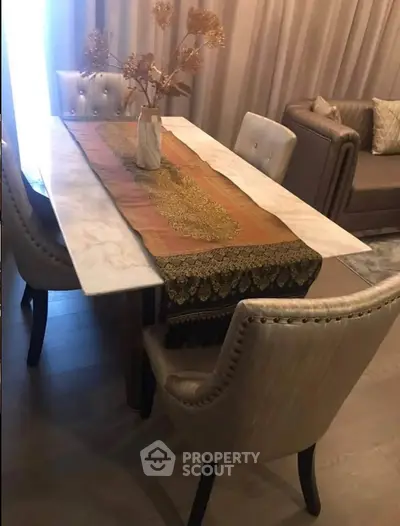 Elegant dining area with marble table and plush chairs in a cozy living room setting.