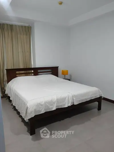 Spacious bedroom with elegant wooden bed and soft lighting, perfect for relaxation.