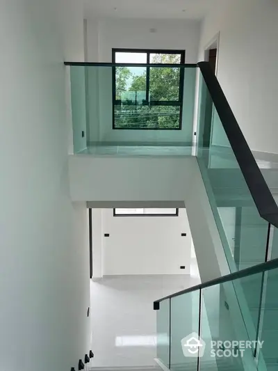 Modern staircase with glass railings and large window view