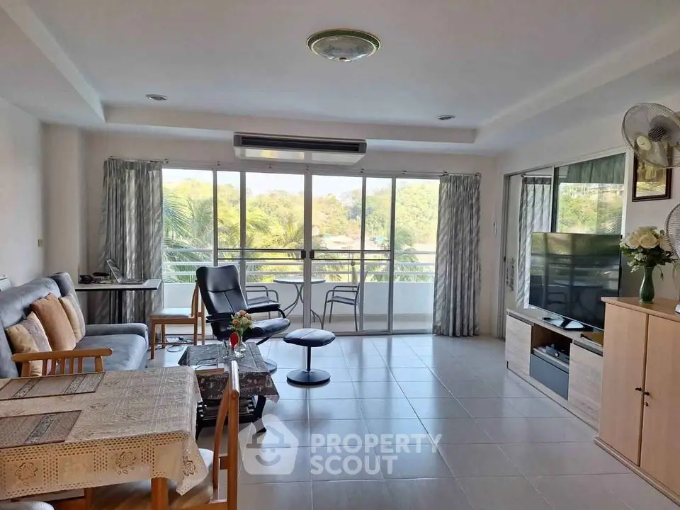 Spacious living room with ample natural light, modern furniture, and a serene balcony view, perfect for relaxation and entertainment.