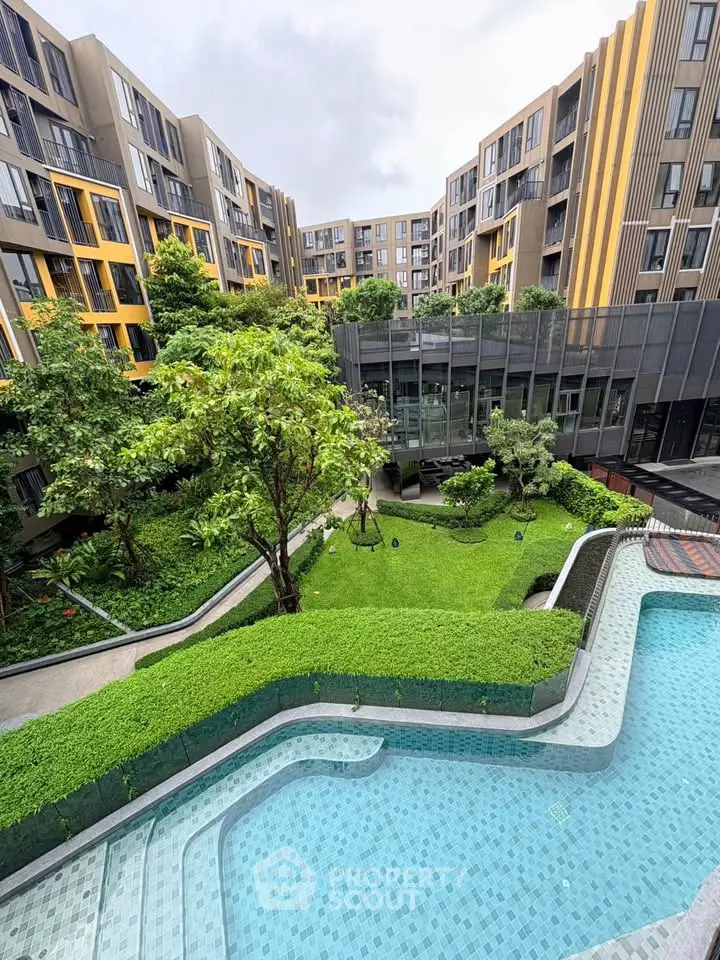 Modern apartment complex with lush garden and pool view, showcasing contemporary architecture and serene outdoor space.