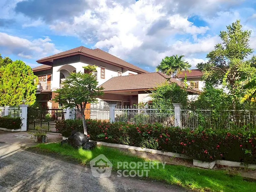 Stunning two-story house with lush garden and elegant fence under a vibrant sky.