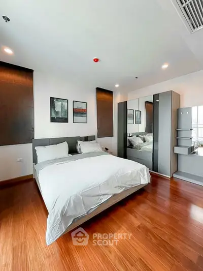 Spacious modern bedroom with wooden flooring and stylish decor