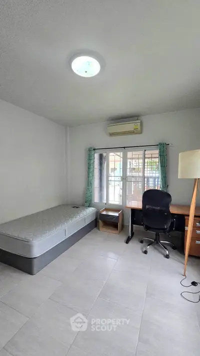 Spacious bedroom with natural light, featuring a single bed, desk, and chair, ideal for a cozy living space.