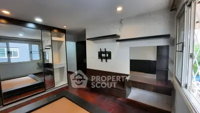 Modern bedroom with built-in shelves and large mirrored wardrobe, perfect for stylish living.