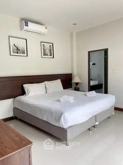 Spacious bedroom with modern decor and ensuite bathroom in a stylish apartment.