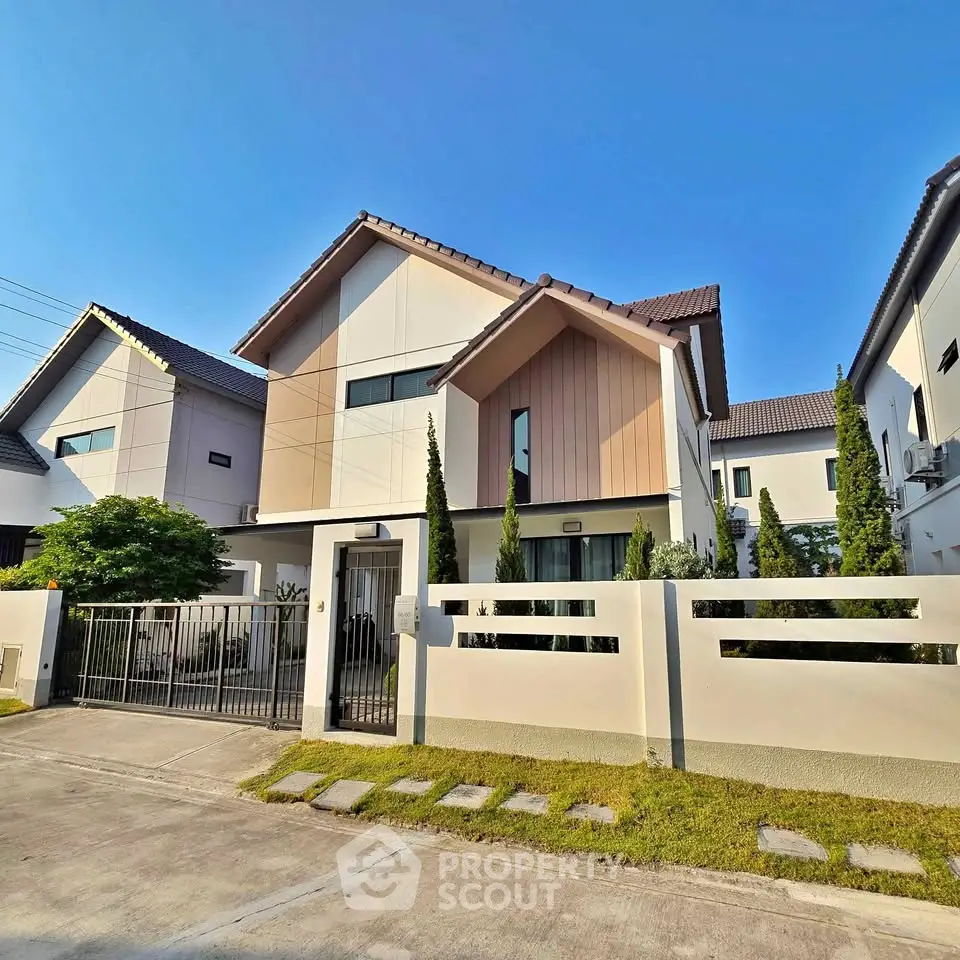 Modern two-story house with sleek design and manicured lawn in a suburban neighborhood.