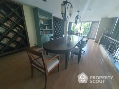 Elegant dining area with large table and bookshelf, featuring natural light and modern decor.