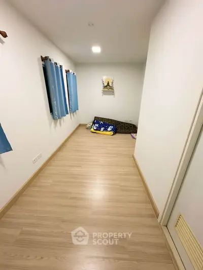 Minimalist room with wooden flooring and blue curtains, ideal for cozy living.