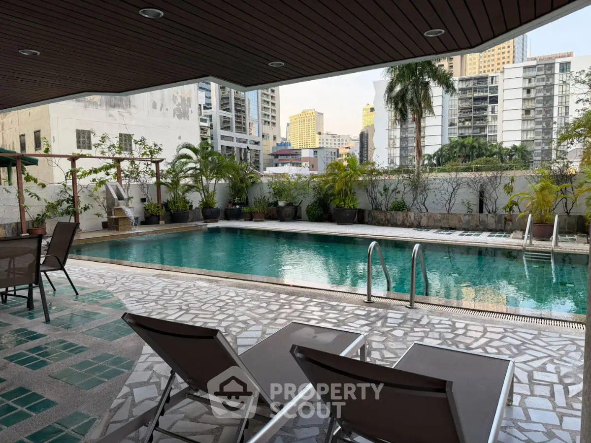 Luxurious outdoor pool area with city views and lush greenery, perfect for relaxation and leisure.