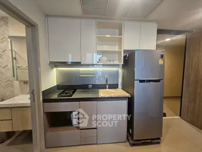 Modern kitchen with sleek cabinets, stainless steel fridge, and electric stove in a compact layout.