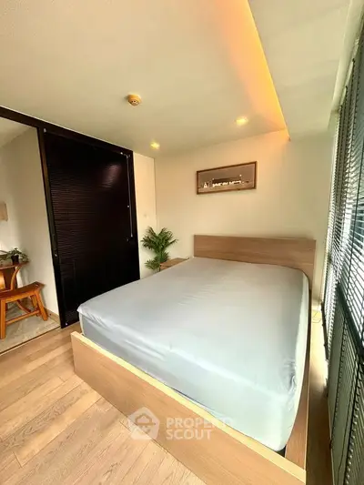 Modern bedroom with sleek design and natural light, featuring a cozy bed and stylish decor.