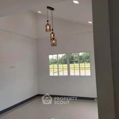 Bright room with modern pendant lights and large window overlooking greenery.