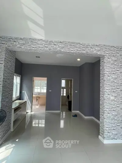 Spacious modern living area with stylish stone accent walls and glossy tiled flooring.