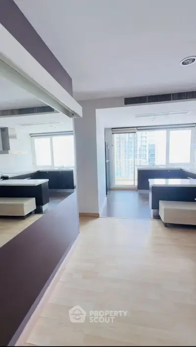 Spacious modern apartment with open kitchen and city view, featuring sleek design and ample natural light.