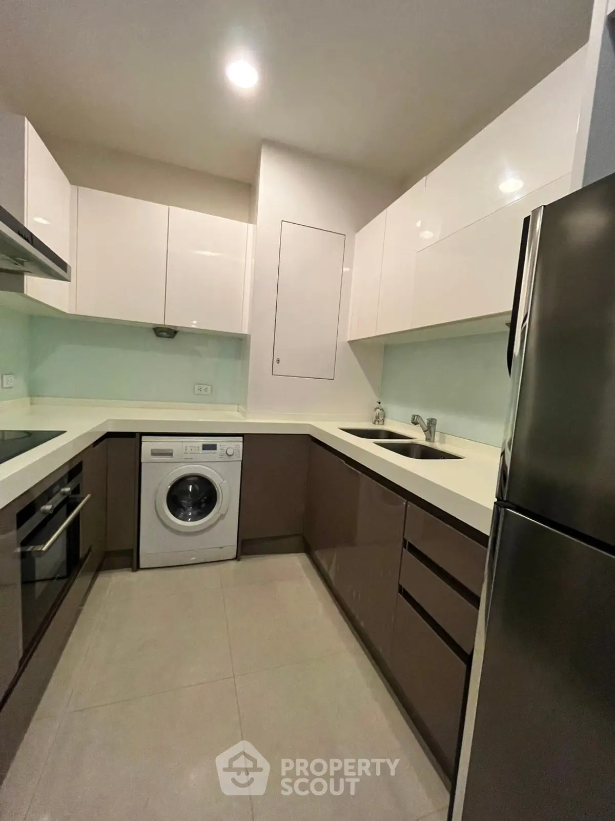 Modern kitchen with sleek cabinets, stainless steel appliances, and washing machine.