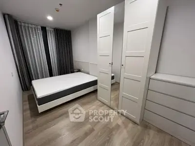 Modern minimalist bedroom with sleek wardrobe and large window.