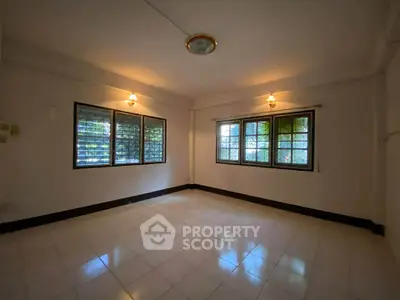 Spacious empty room with large windows and tiled flooring, perfect for customization.