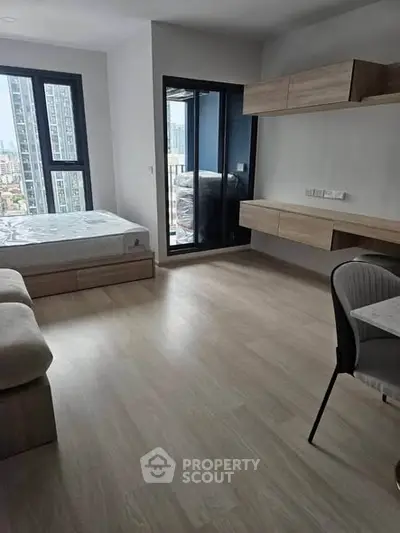Modern bedroom with large windows and built-in storage in a high-rise apartment.