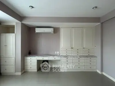Spacious study room with built-in desk and ample storage in modern apartment.