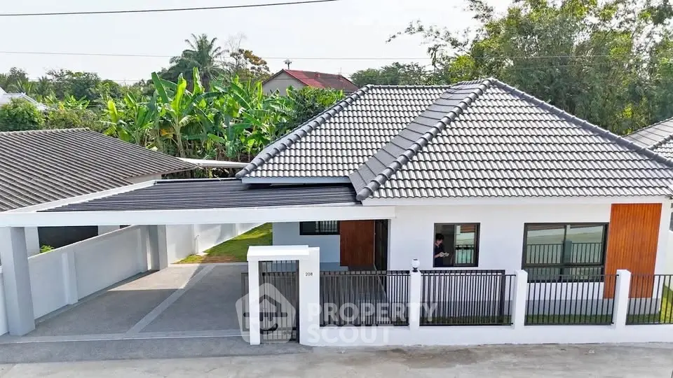 Charming single-story home with modern roof tiles and spacious carport in lush green setting.