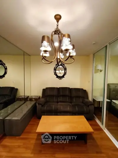 Elegant living room with leather sofa, mirrored wall, and stylish chandelier