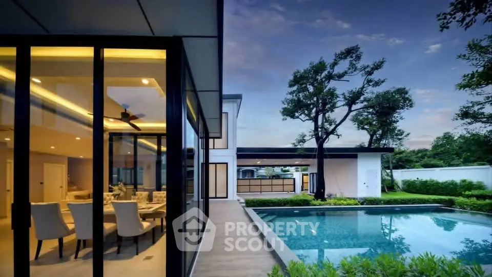 Luxurious modern home with pool and elegant interior dining area, surrounded by lush greenery.