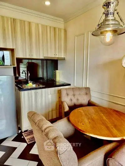 Chic kitchen with cozy dining area, featuring modern cabinetry and stylish lighting in a compact space.