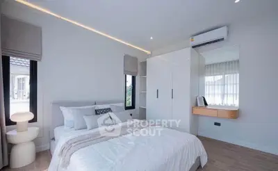 Modern bedroom with sleek design and natural light, featuring a cozy bed and built-in wardrobe.