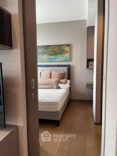 Modern bedroom with stylish decor and wooden flooring, featuring a comfortable bed and elegant artwork.