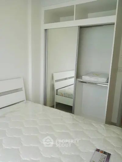 Modern bedroom with sleek white furniture and mirrored closet doors