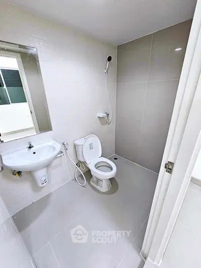 Modern bathroom with sleek design, featuring a shower, toilet, and sink in a compact layout.