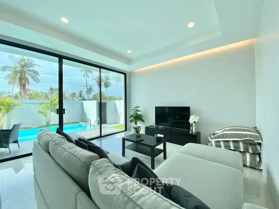 Modern living room with pool view, featuring sleek furniture and large glass doors for natural light.