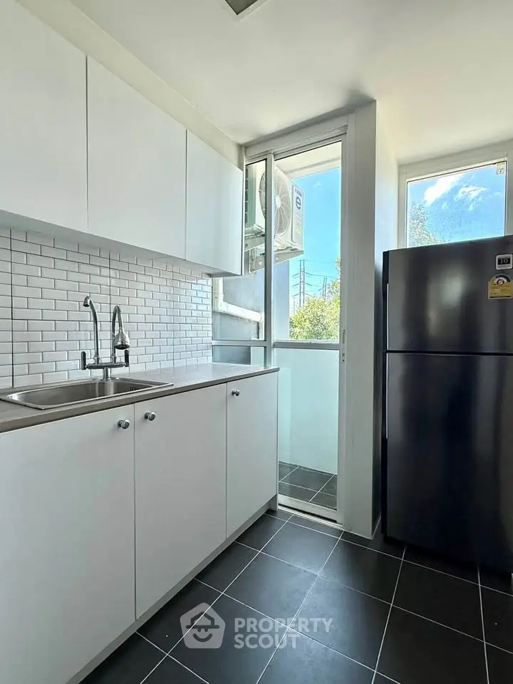 Modern kitchen with sleek cabinets and large fridge in bright apartment