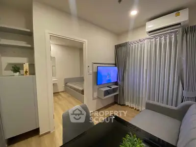 Modern living room with sleek furniture and wall-mounted TV in a cozy apartment setting.