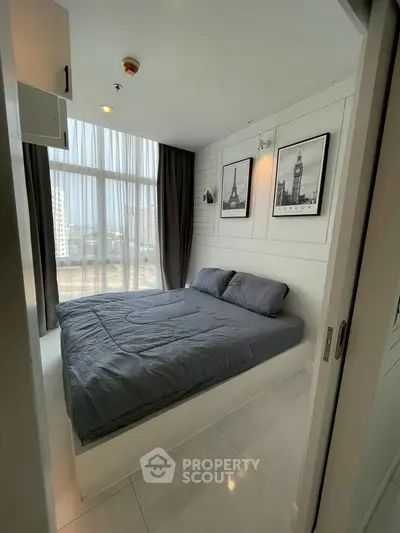 Modern bedroom with large window and city view, featuring stylish decor and cozy bedding.