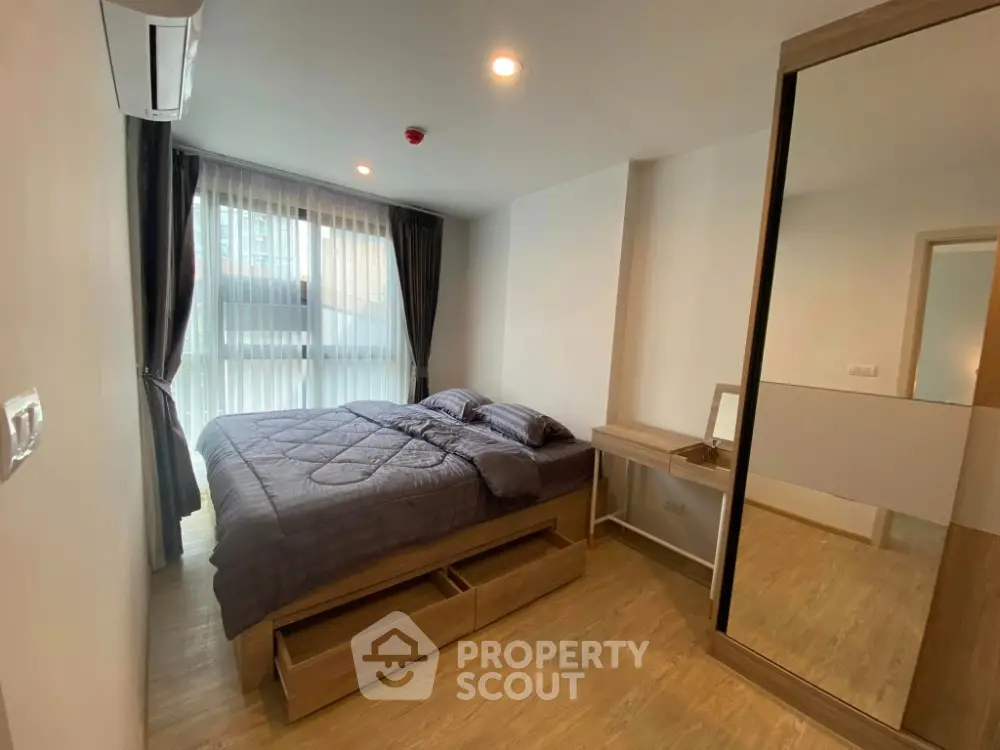 Modern bedroom with large window, wooden flooring, and sleek furniture in a stylish apartment.