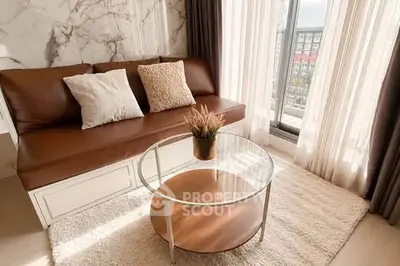 Stylish living room with leather sofa, glass coffee table, and large window view.