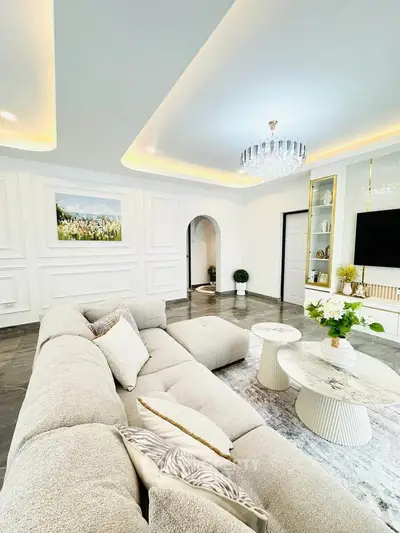 Luxurious living room with elegant decor, plush sectional sofa, and modern chandelier in a stylish home.