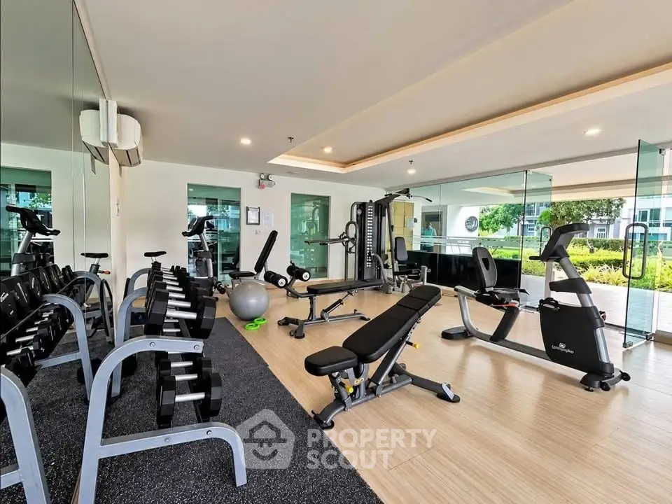 Modern gym with state-of-the-art equipment and large windows offering garden views.