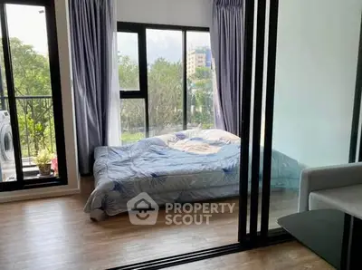 Cozy bedroom with large windows and balcony access, offering a serene view and natural light.